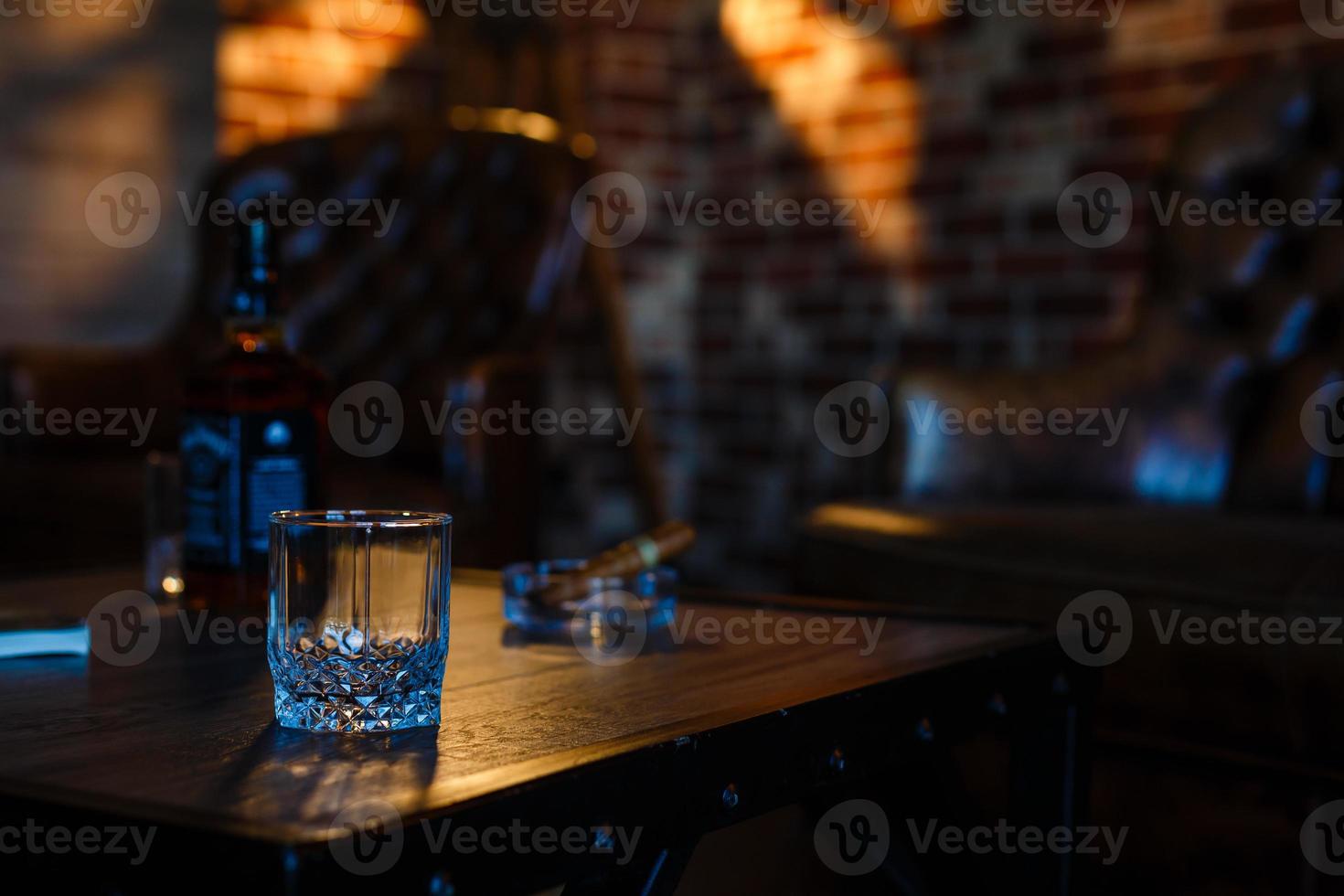 glasögon av whisky med rökning cigarr och is kuber på trä- tabell foto