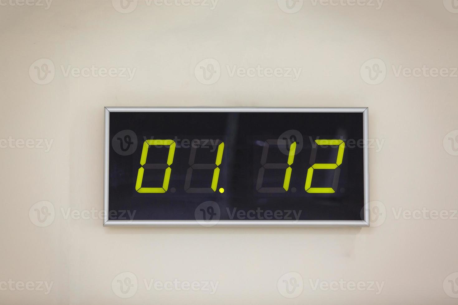 svart digital klocka på en vit bakgrund som visar tid 01.12 foto