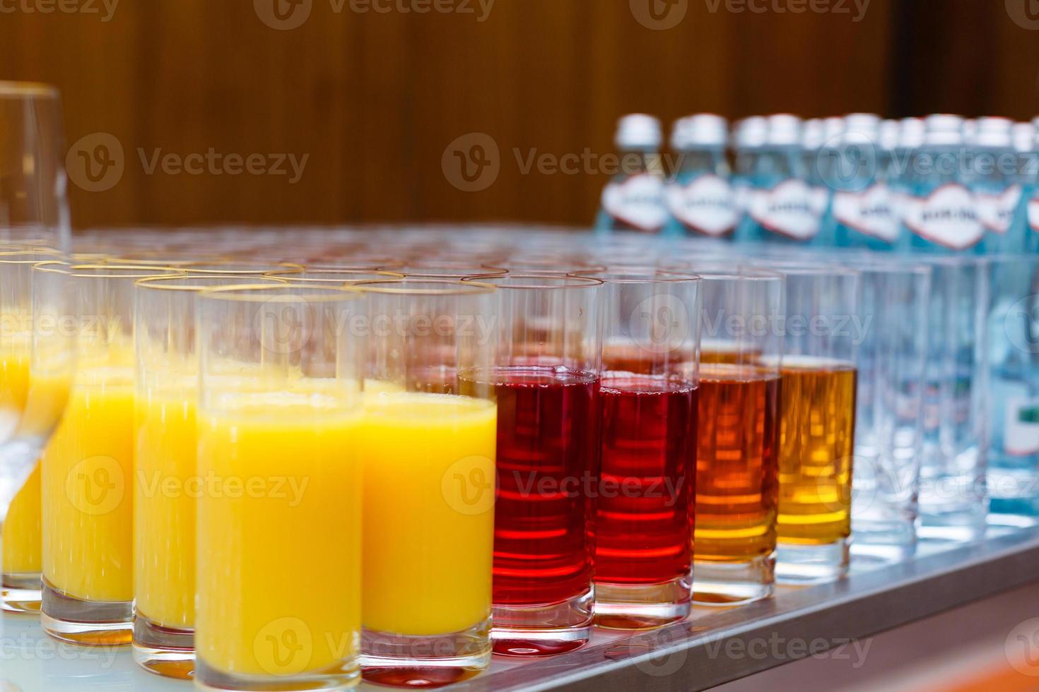 mat bakgrund. många glasögon med naturlig juice med orange på buffé tabell foto