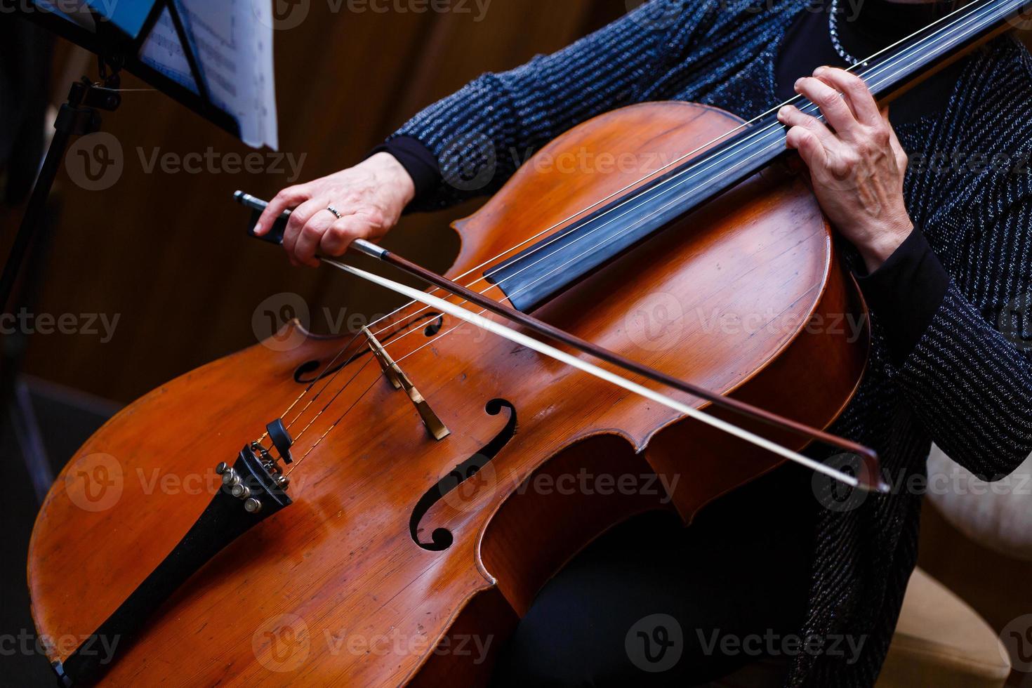 en ung flicka spelar de cello i de mörk. händer på cello foto