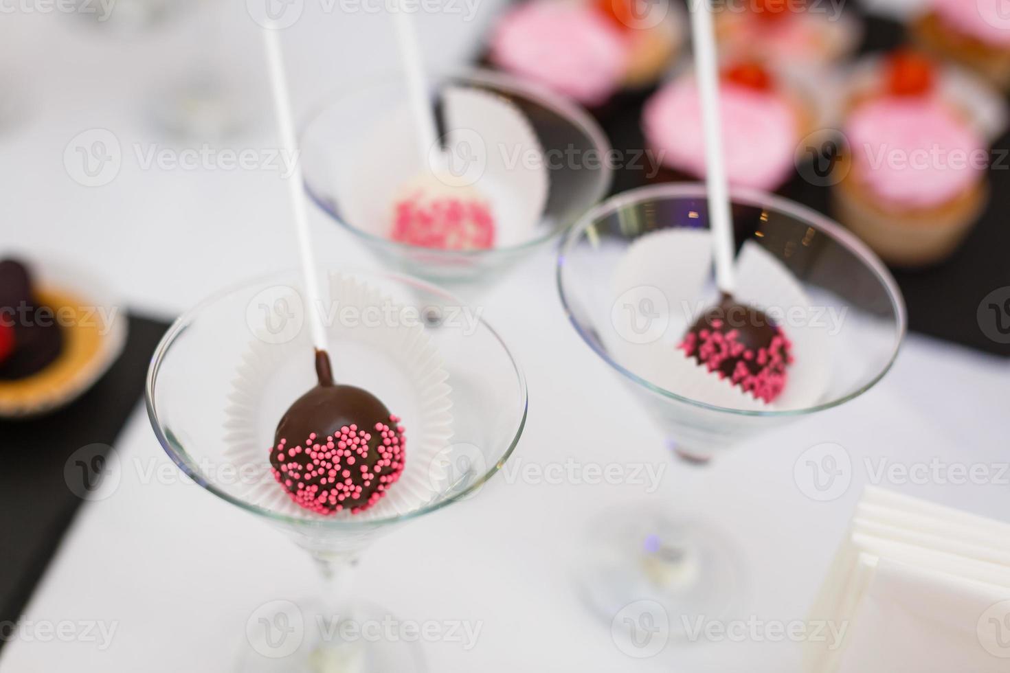 Hem tillverkad choklad kaka pop- dekorerad med rosa och vit socker strössel. foto