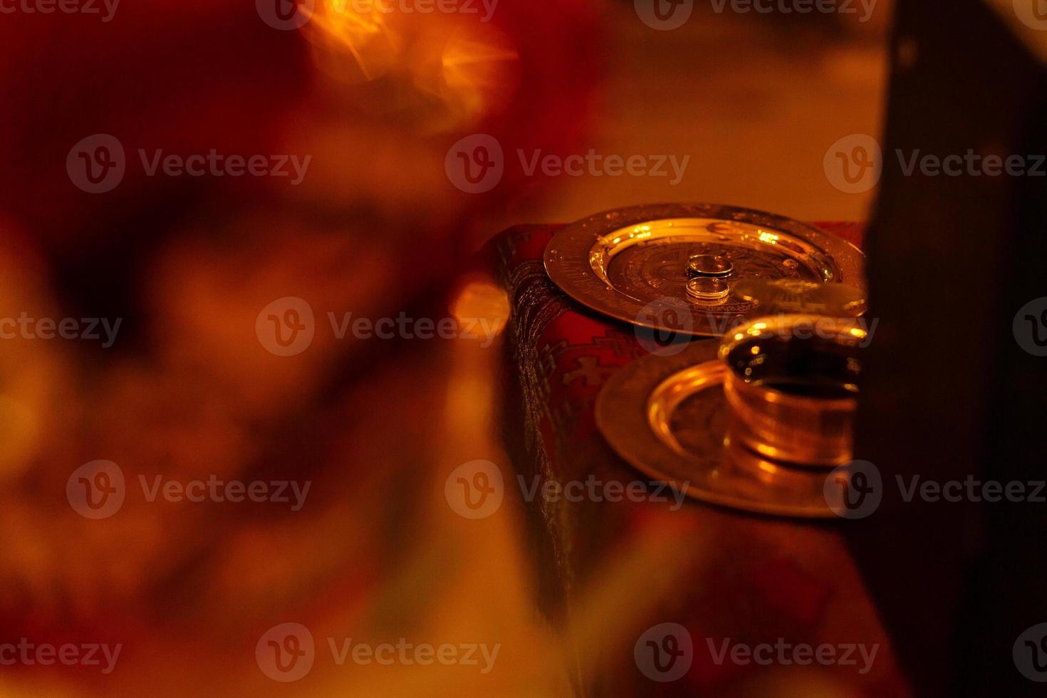 gyllene bröllop ringar på metall tallrik i kyrka med helig vatten. bröllop traditionell ceremoni. Plats för text foto