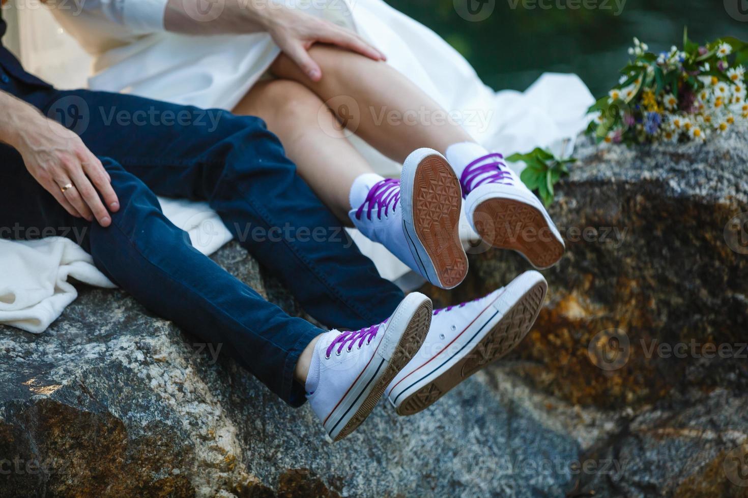 kärlek berättelse berättade förbi stövlar. mänsklig fötter stänga upp. man och kvinna i sneakers. flicka i vit skor. kille i svart gymnastikskor och denim. hipster par i sommar. ben stänga upp. foto