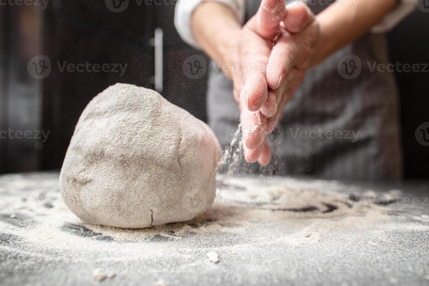 stor klump av knådad deg på de tabell med mjöl, i de bakgrund av de bagare händer. bröd tillverkning. foto