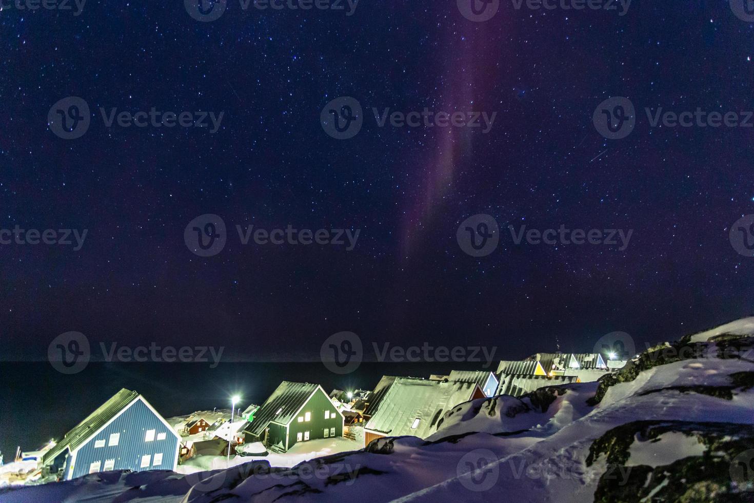 arktisk polär natt över färgrik inuit hus med små nordlig ljus i en förort av arktisk huvudstad nuuk, Grönland foto
