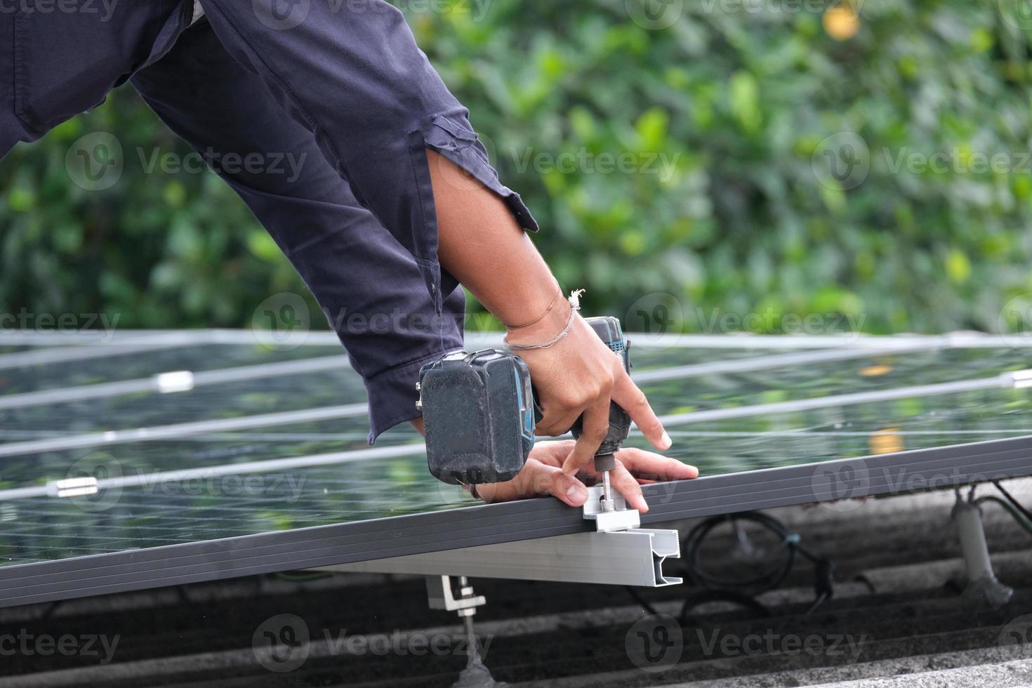 elektriker manlig använda sig av sladdlös elektrisk borra arbetssätt Installera aluminium järnväg . professionell tekniker arbetstagare miljö ansluta elektrisk metall på tak hus för sol- cell foto