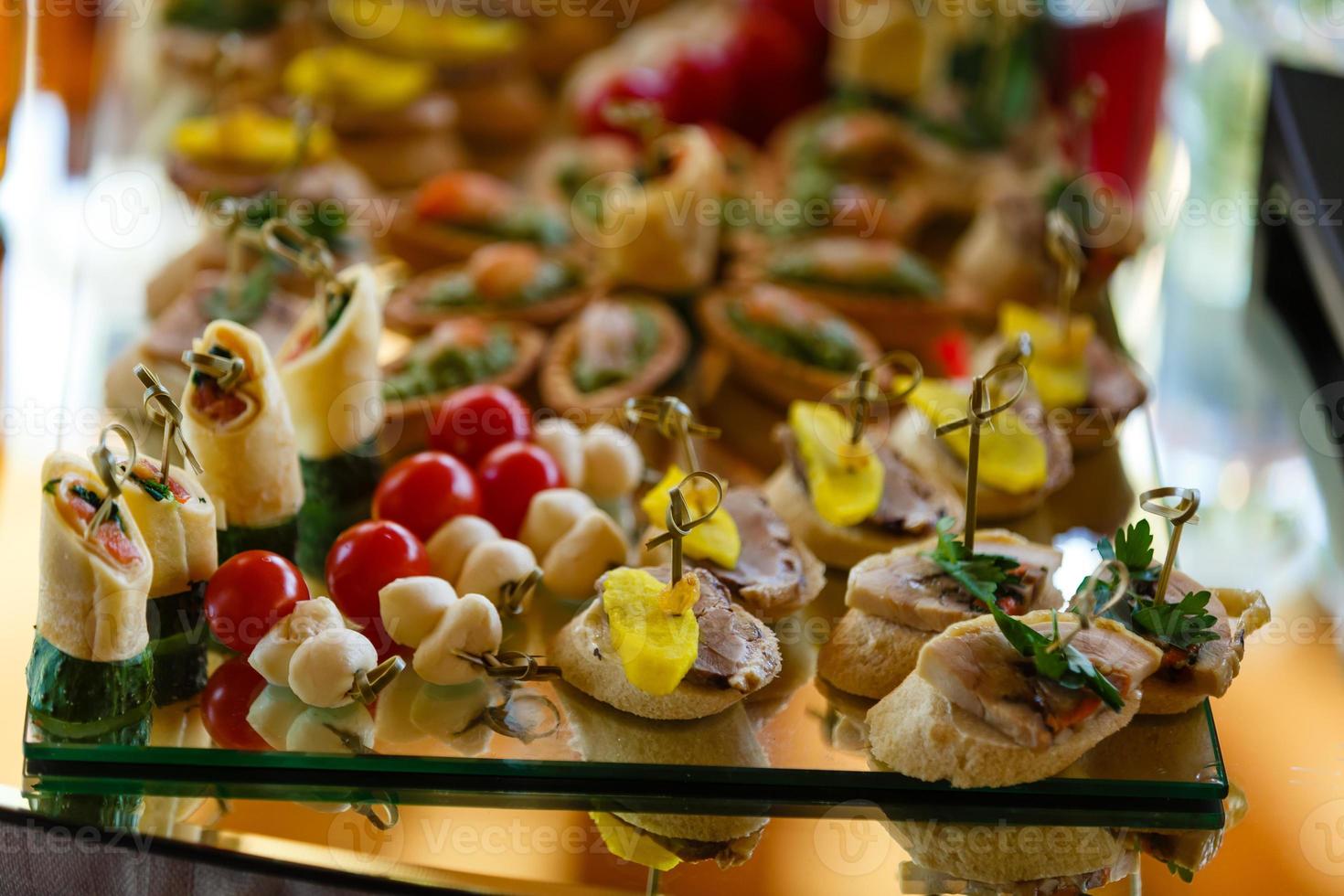 vackert dekorerad catering bankett tabell med hamburgare, profiteroler, sallader och kall snacks. mängd av gott utsökt snacks på de tabell foto