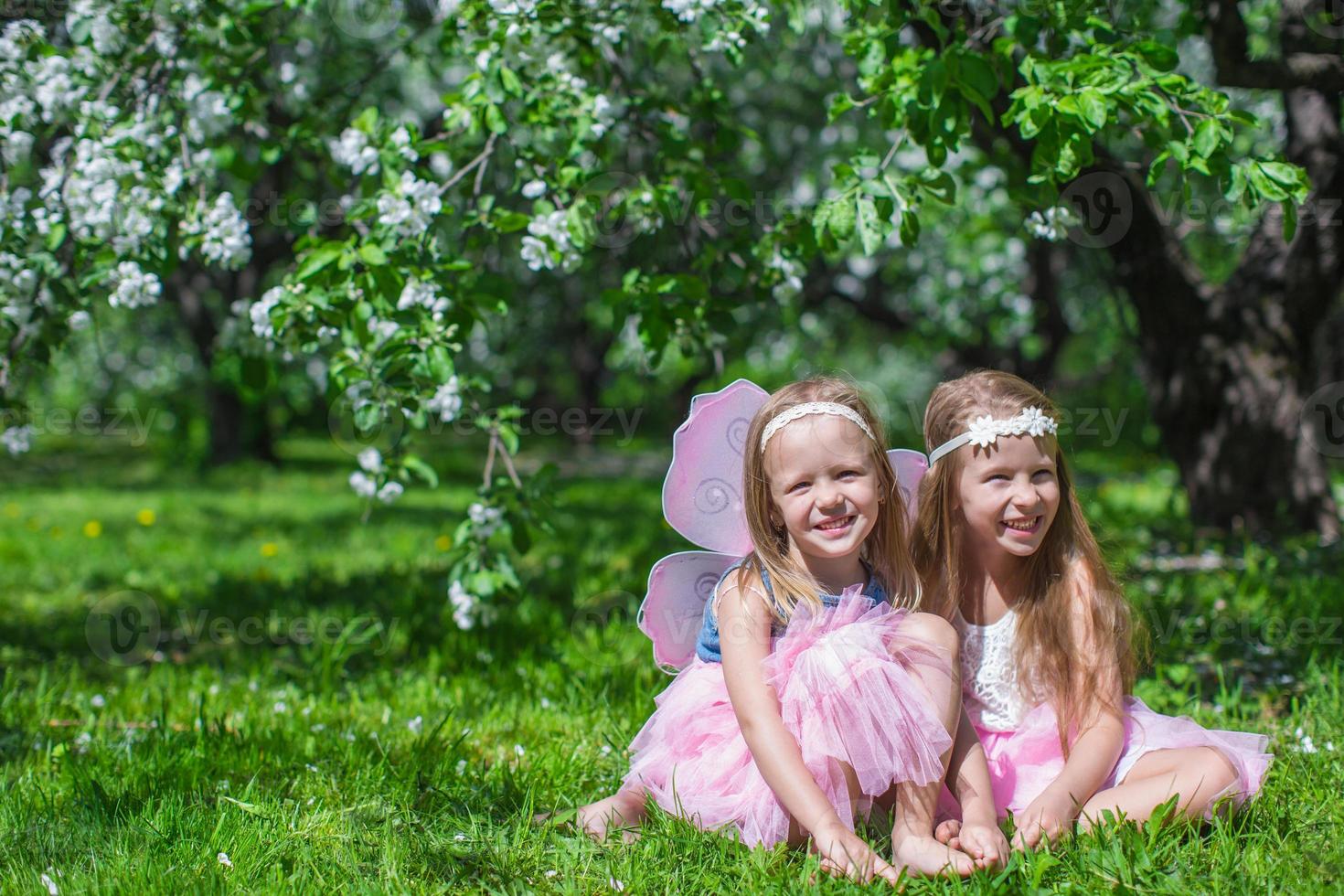 liten förtjusande flickor med fjäril vingar i de blomstrande äpple fruktträdgård foto