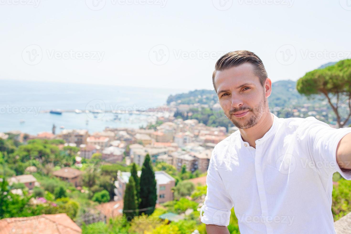 Lycklig ung man tar selfie bakgrund de gammal kust stad rapallo i liguria foto