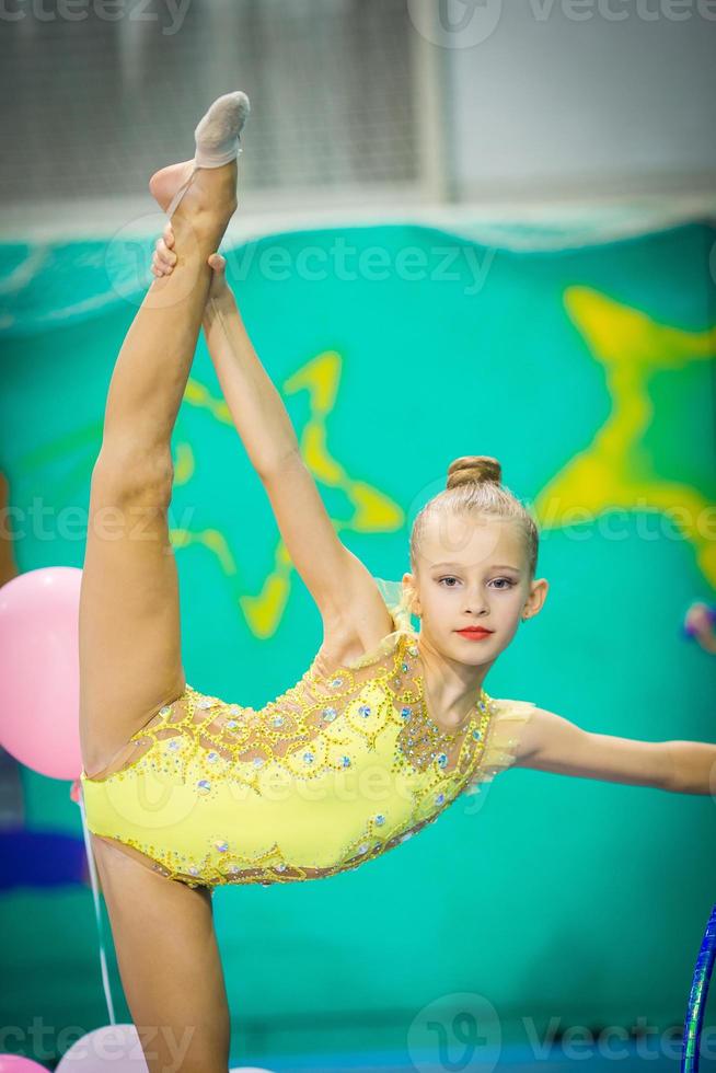 liten aktiva skön gymnast i tävlingar av rytmisk gymnastik foto