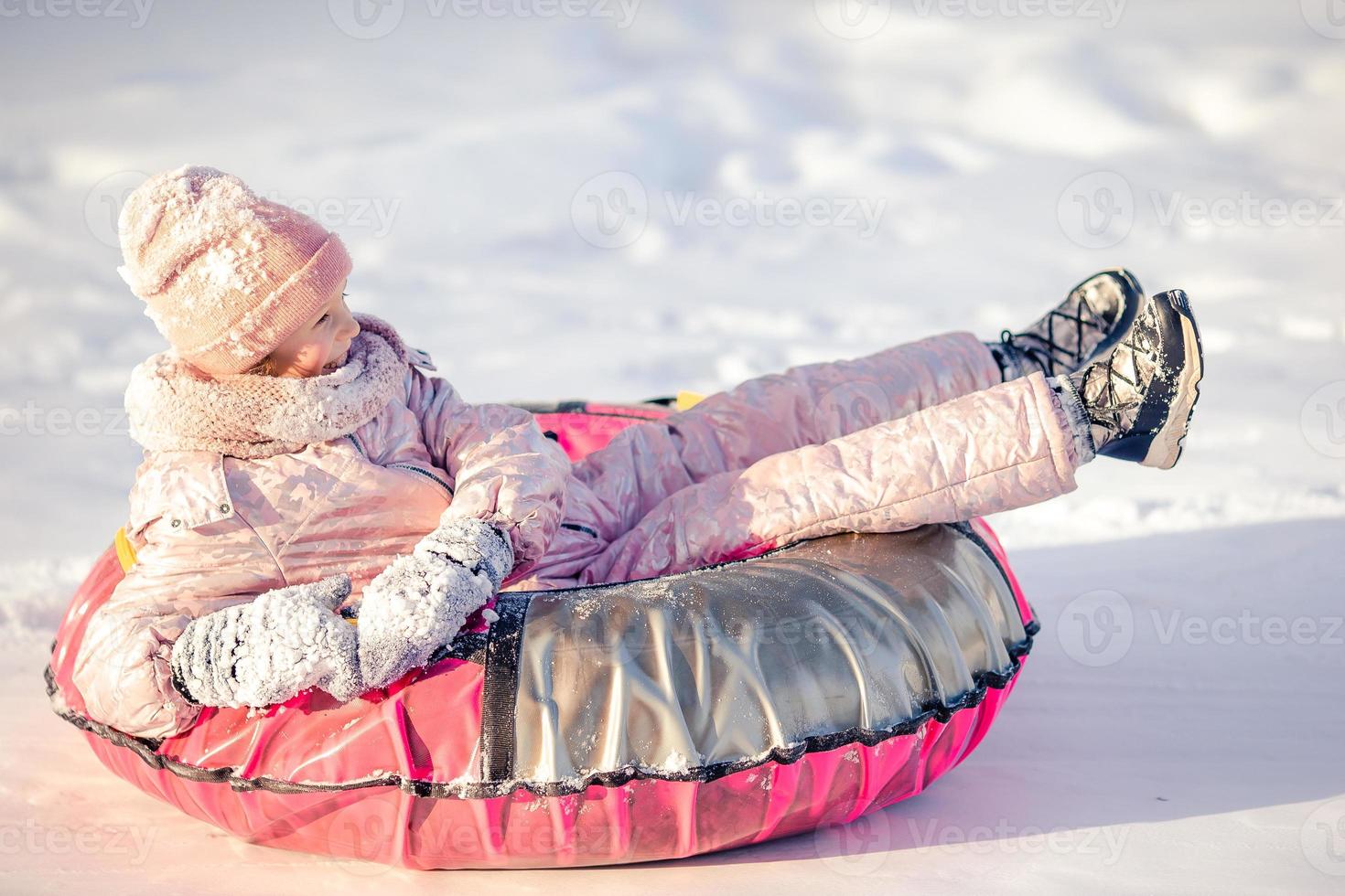 förtjusande liten Lycklig flicka sledding i vinter- snöig dag. foto