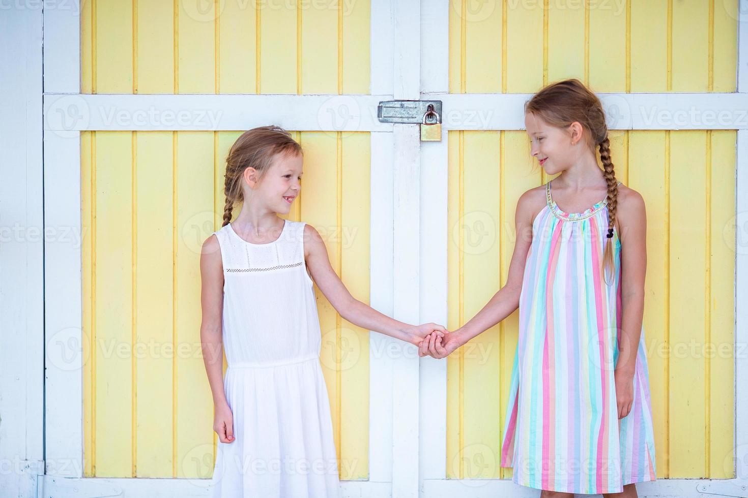 förtjusande liten flickor på sommar semester bakgrund traditionell karibiska hus foto