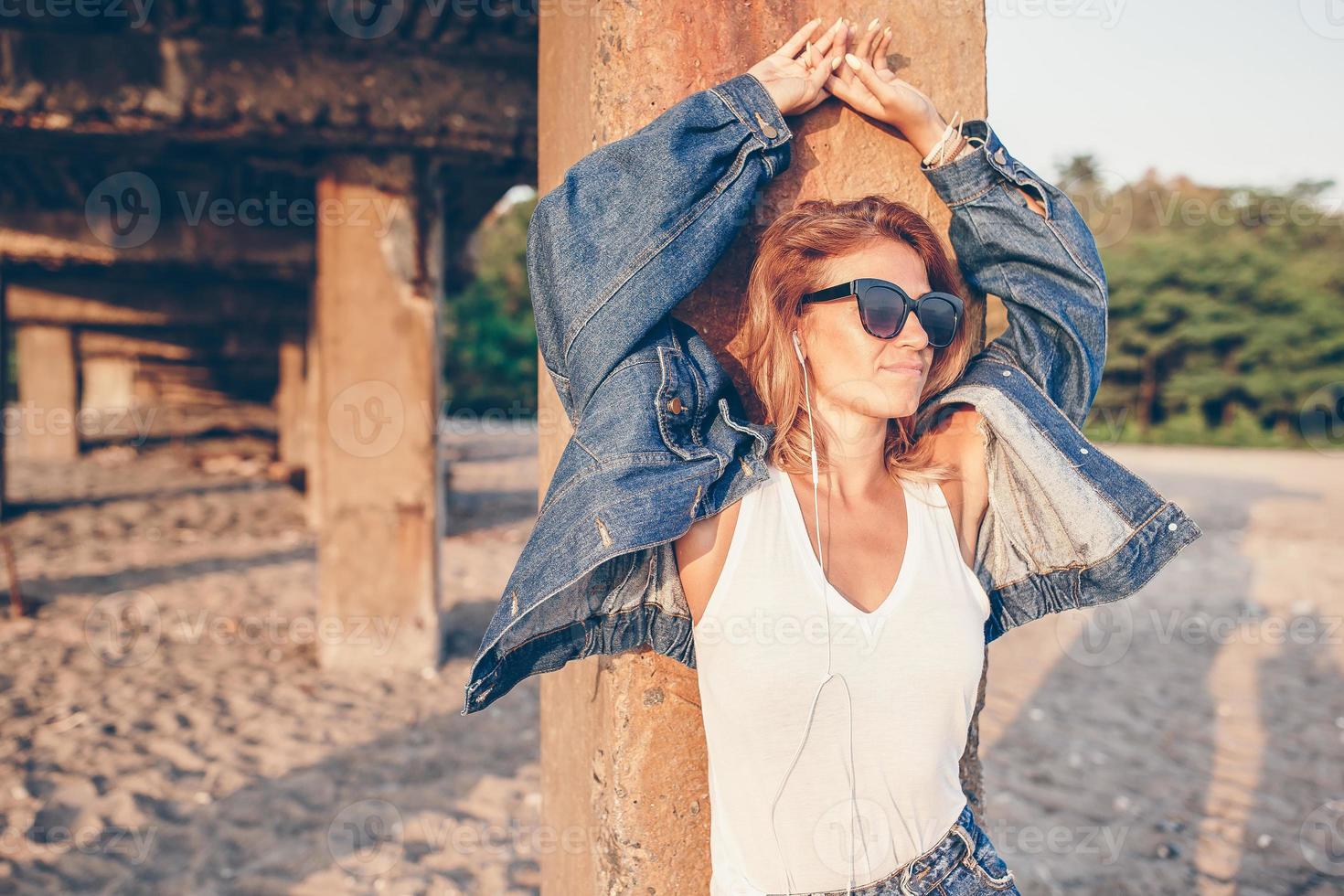 utomhus- mode porträtt av eleganta flicka bär jeans jacka på de strand. foto