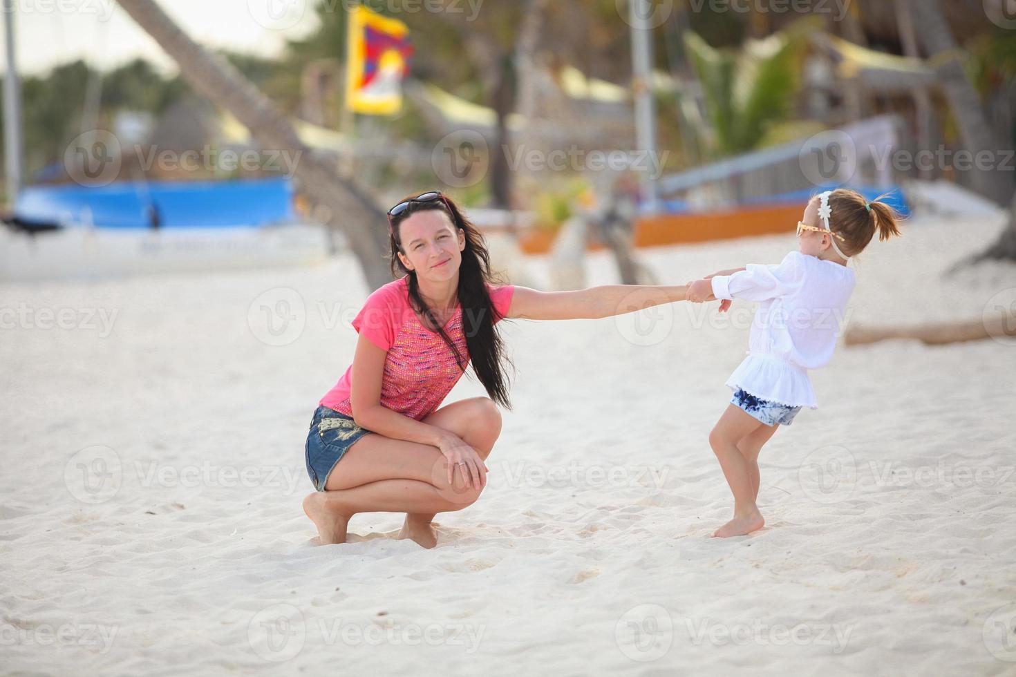 närbild liten flicka är innehav henne ung mor på de strand foto