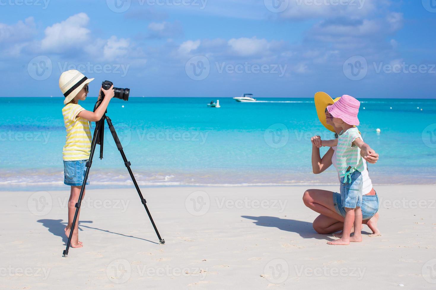 liten flicka framställning Foto av henne mamma och syster på de strand