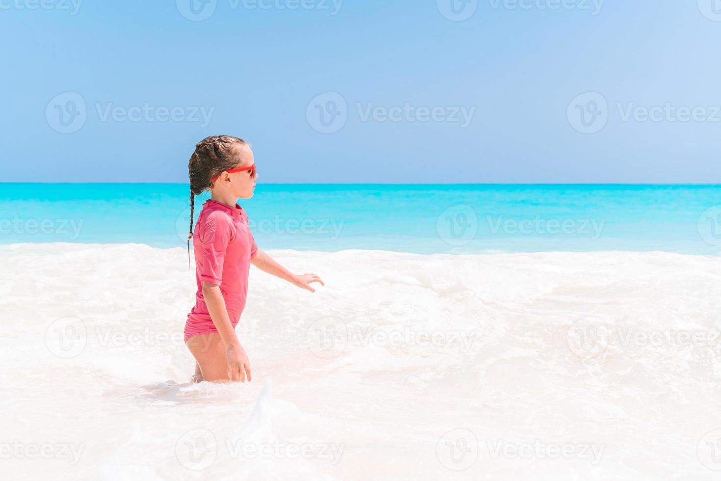 bedårande liten flicka ha kul på den tropiska stranden under semestern foto