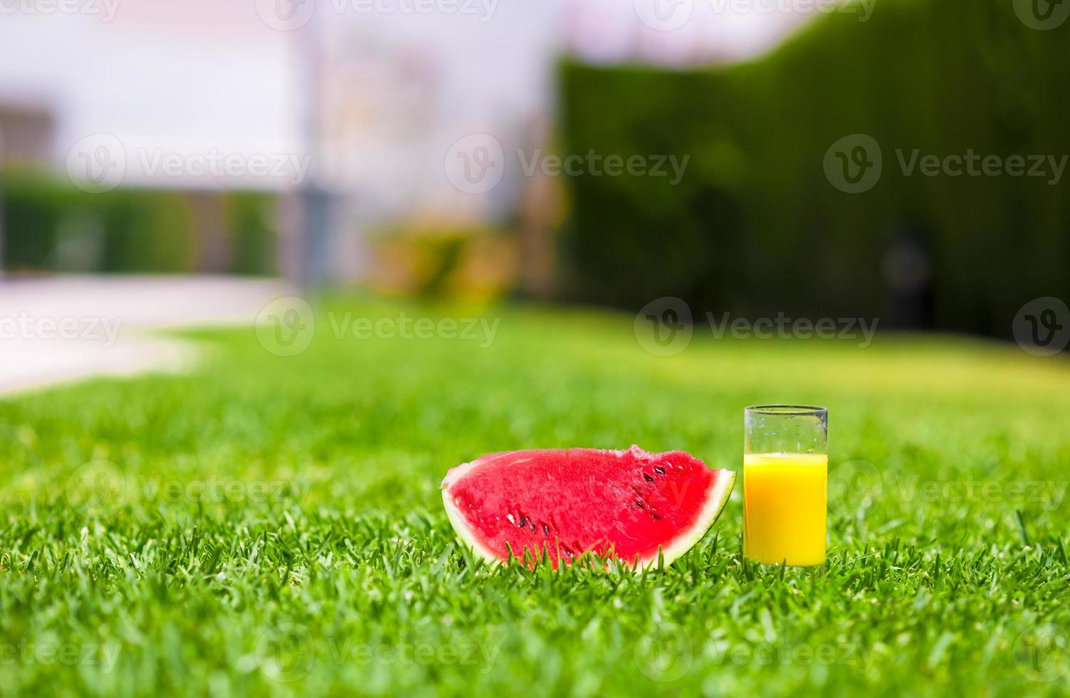 röd mogen skiva vattenmelon och glas av orange juice på grön gräs foto