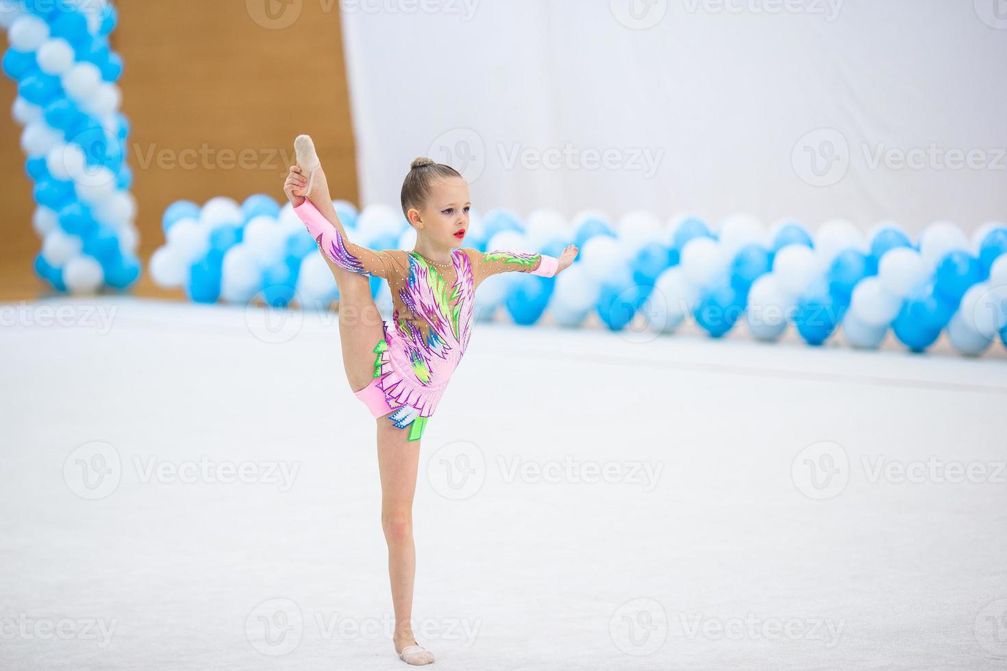 skön liten gymnast flicka med henne prestanda på de matta foto