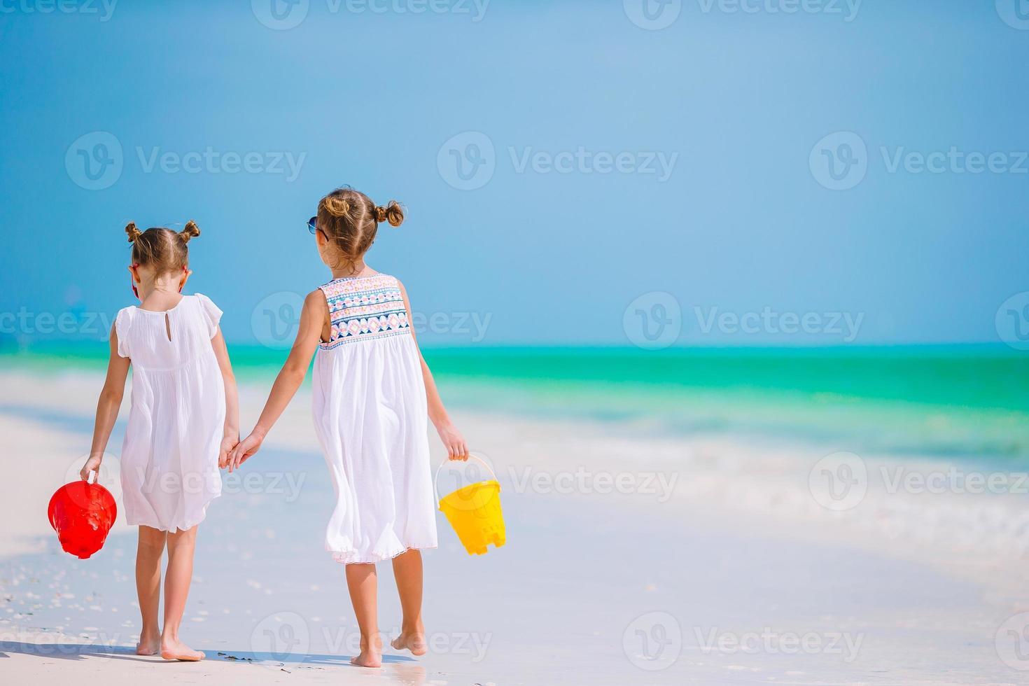 förtjusande liten flickor ha roligt tillsammans på vit tropisk strand foto