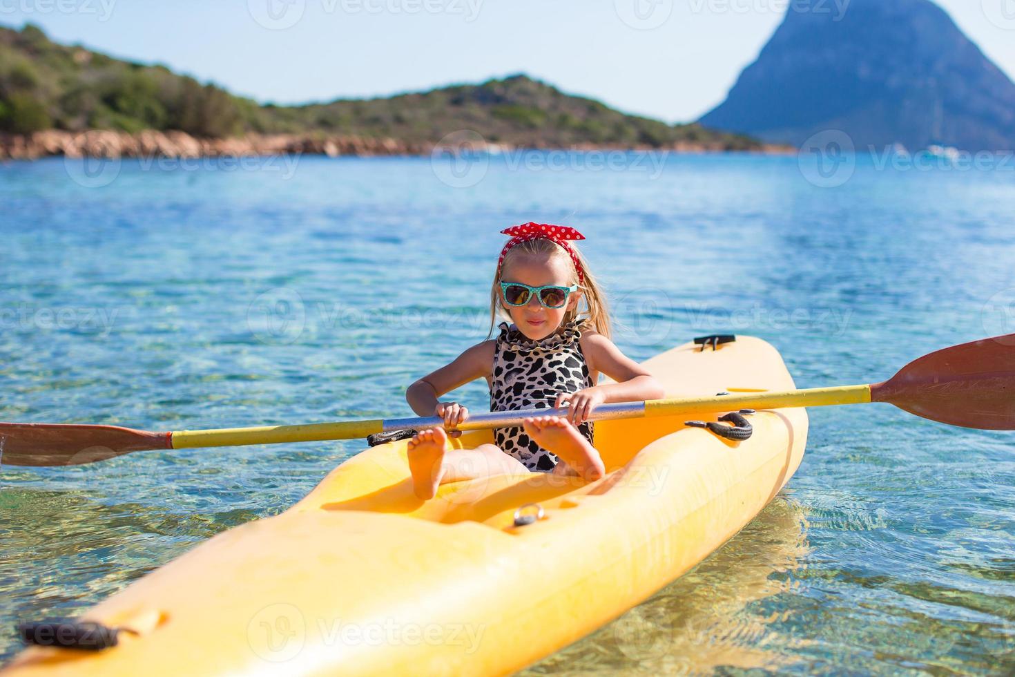 liten Lycklig söt flicka njut av Kajakpaddling i de klar blå hav foto
