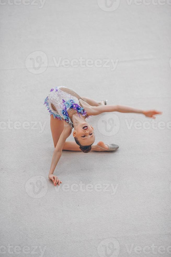 skön liten aktiva gymnast flicka med henne prestanda på de matta foto