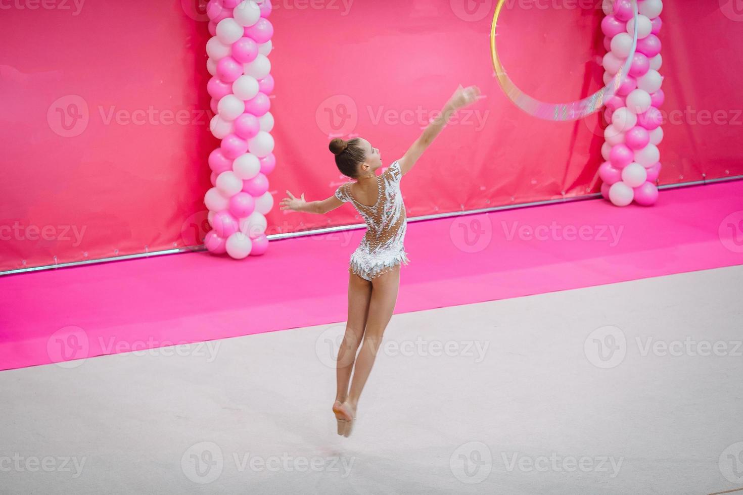 liten gymnast Träning på de matta och redo för tävlingar foto