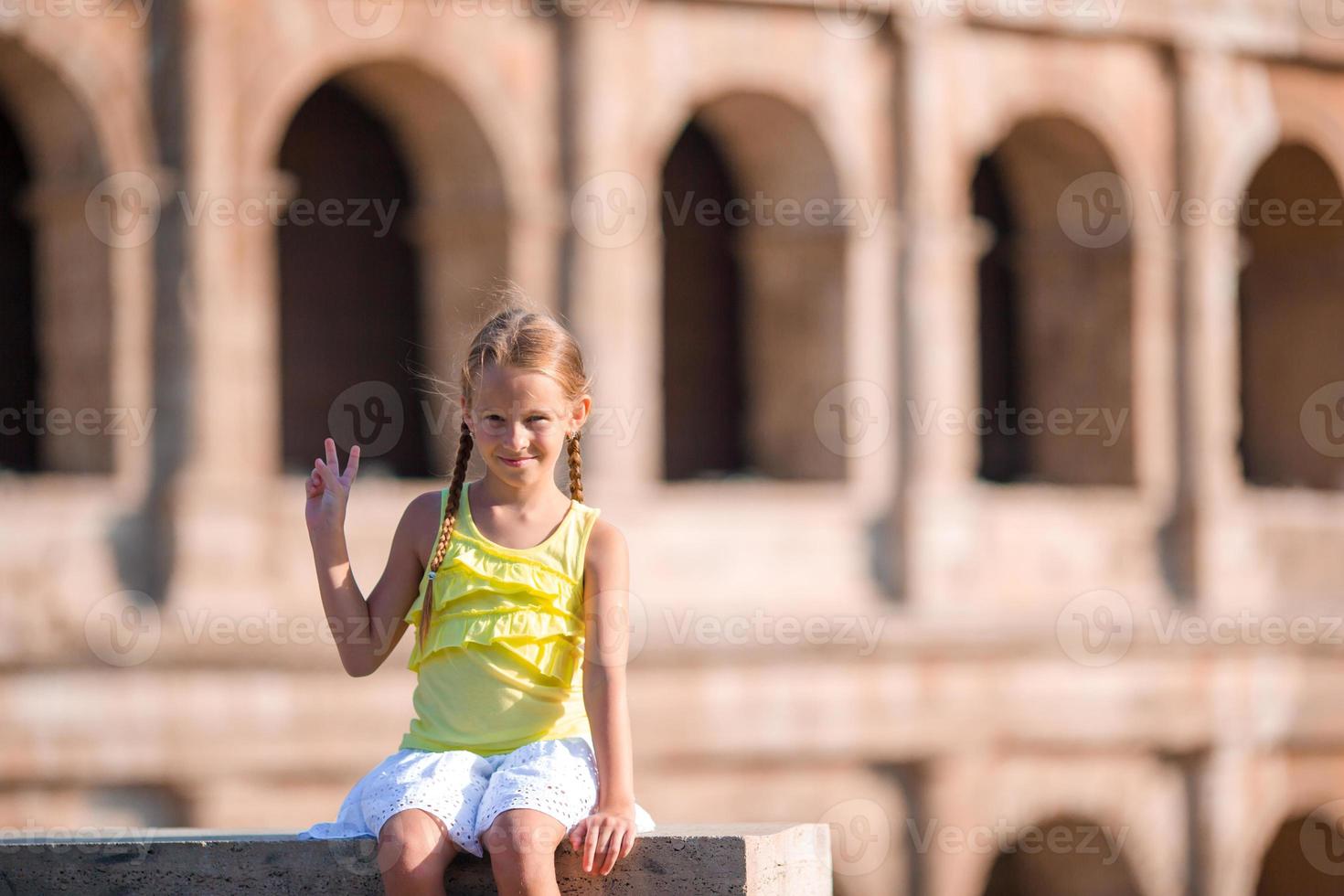 förtjusande liten aktiva flicka har roligt i främre av colosseum i rom, Italien. unge utgifterna barndom i Europa foto