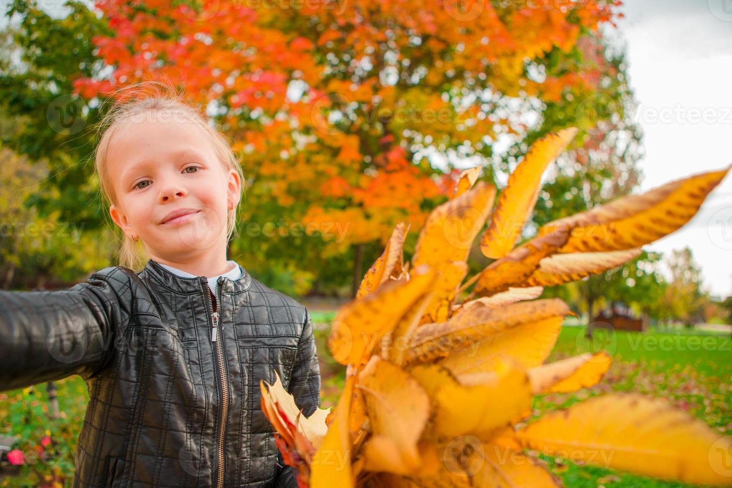 liten flicka tar selfie porträtt med gul och orange löv bukett i fa foto