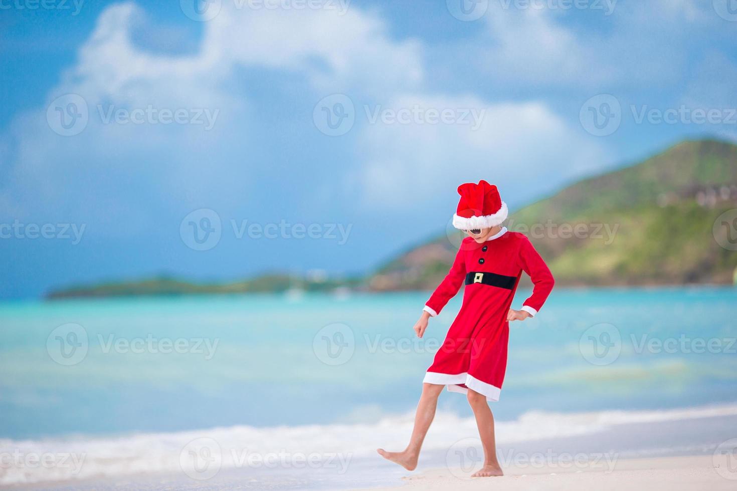 bedårande liten flicka i santa hatt på tropisk strand foto