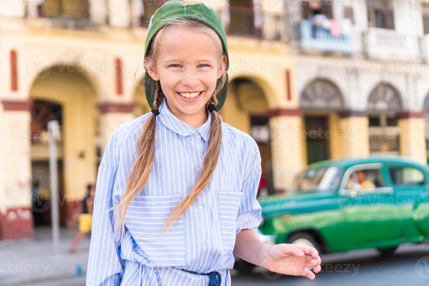 förtjusande liten flicka i populär område i gammal Havanna, kuba. porträtt av unge bakgrund årgång klassisk amerikan bil foto
