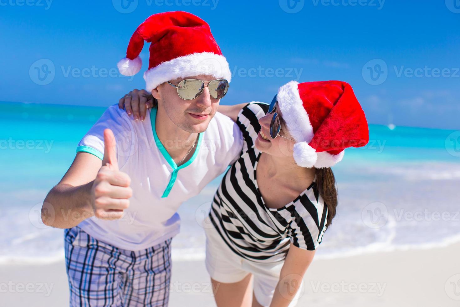 ung romantisk par i santa hattar under strand semester foto