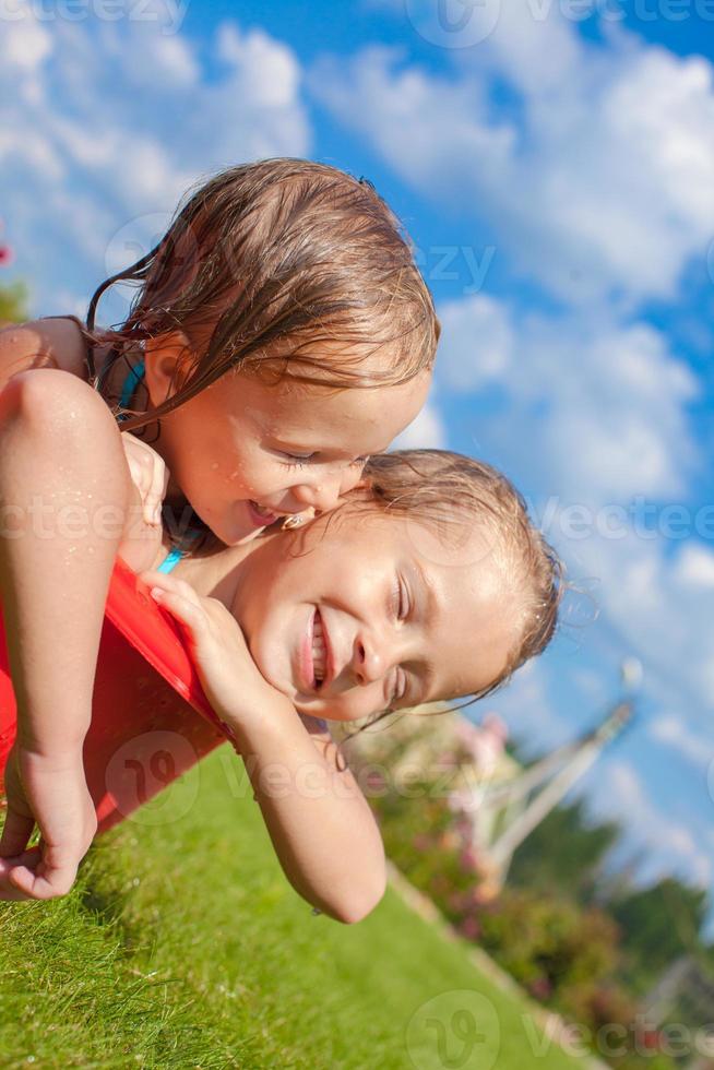 två charmig liten Lycklig systrar har roligt i små slå samman på de gård utomhus- foto