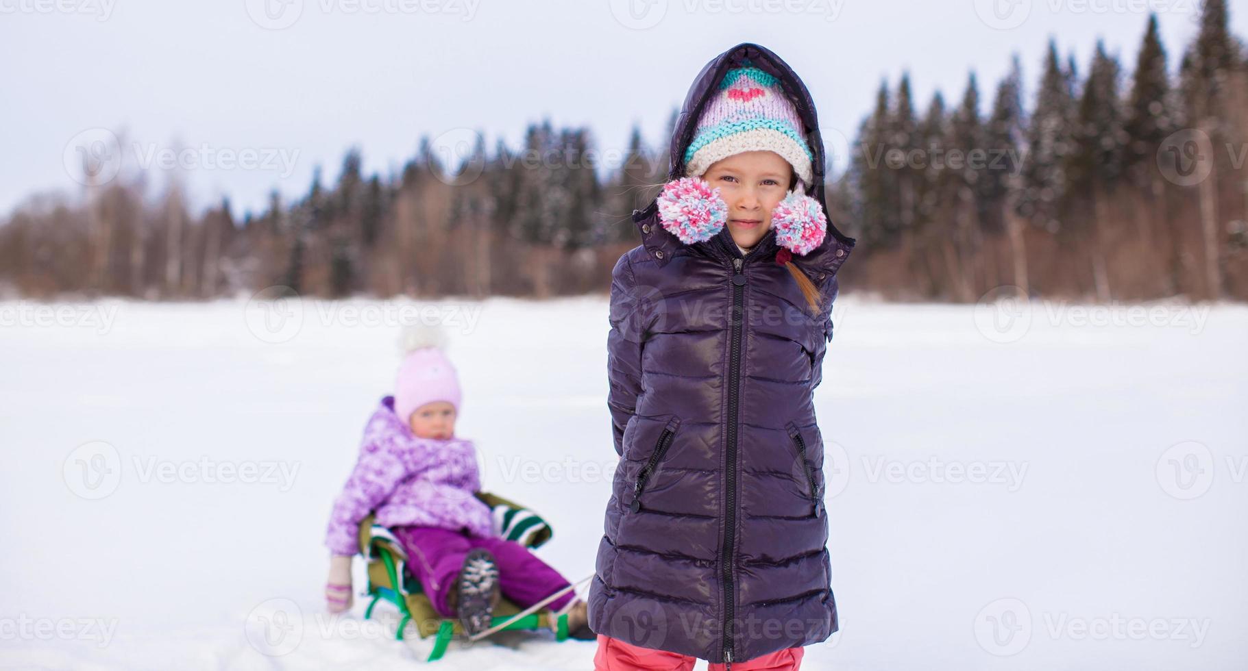 förtjusande liten Lycklig flicka sledding henne syster foto