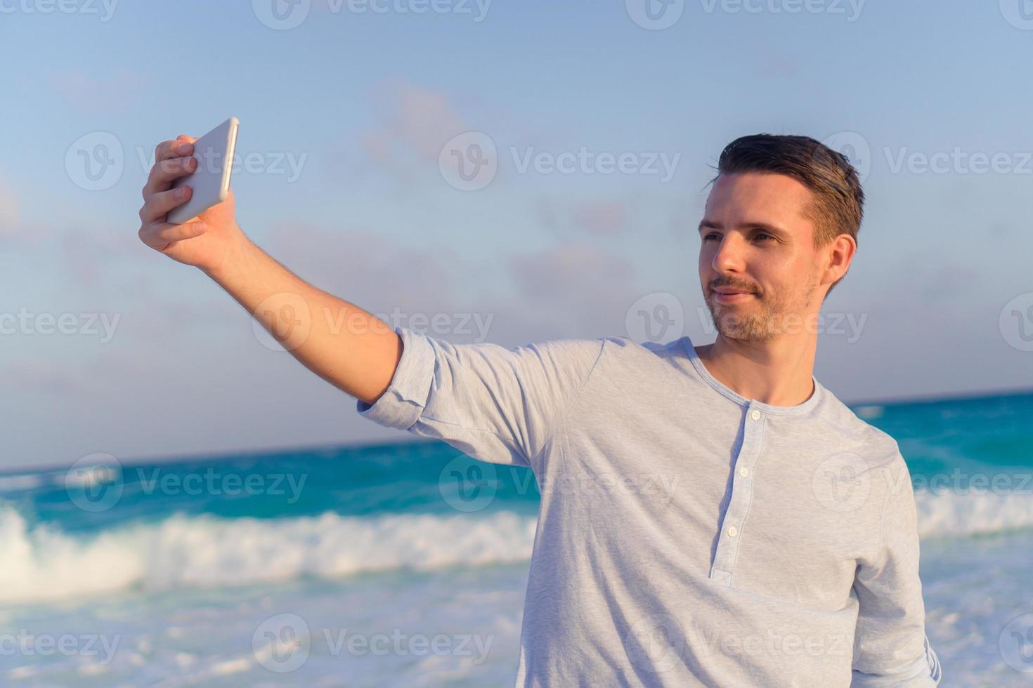 ung man tar selfie på de strand bakgrund de hav foto