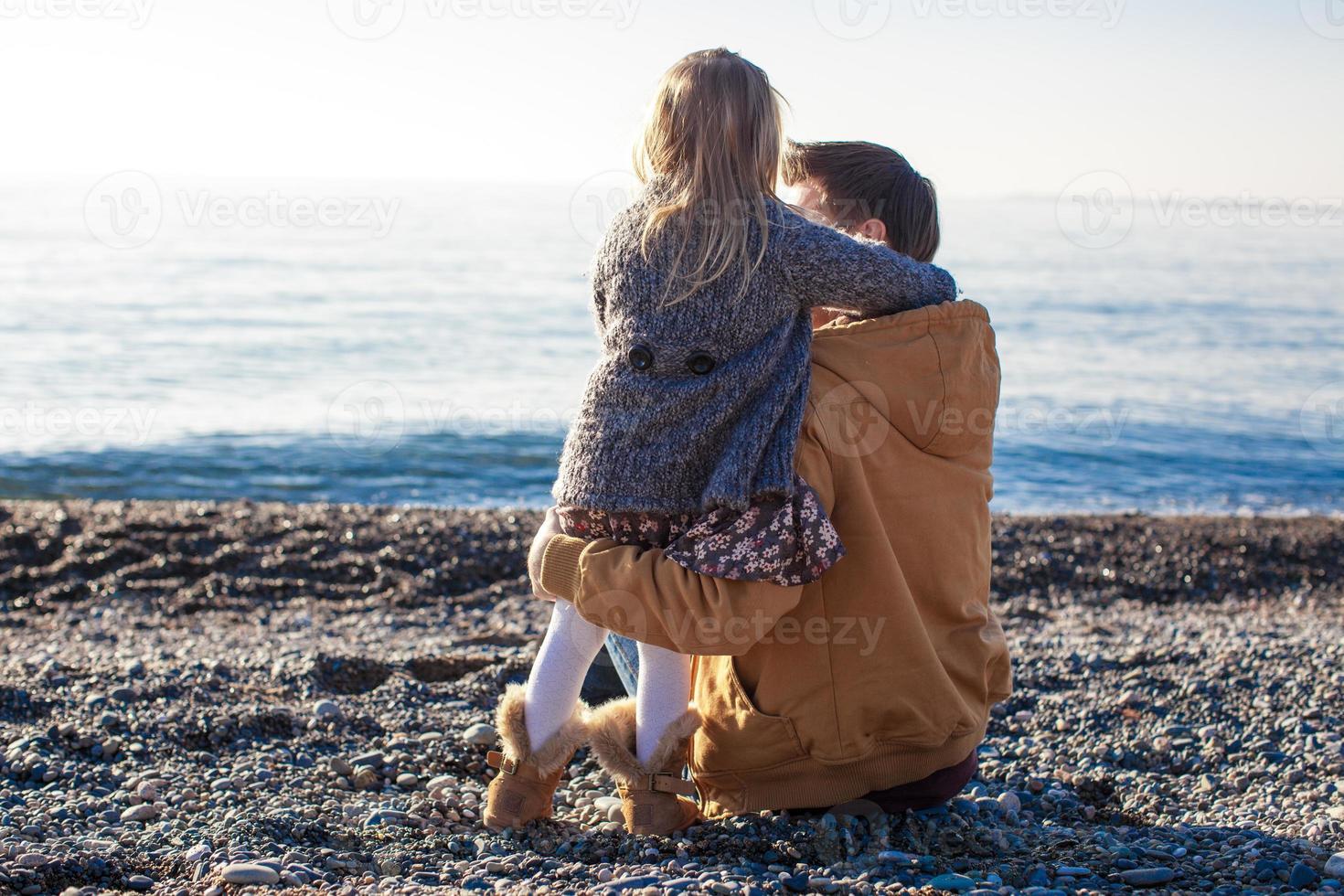 ung far och liten flicka på de strand på en solig vinter- dag foto