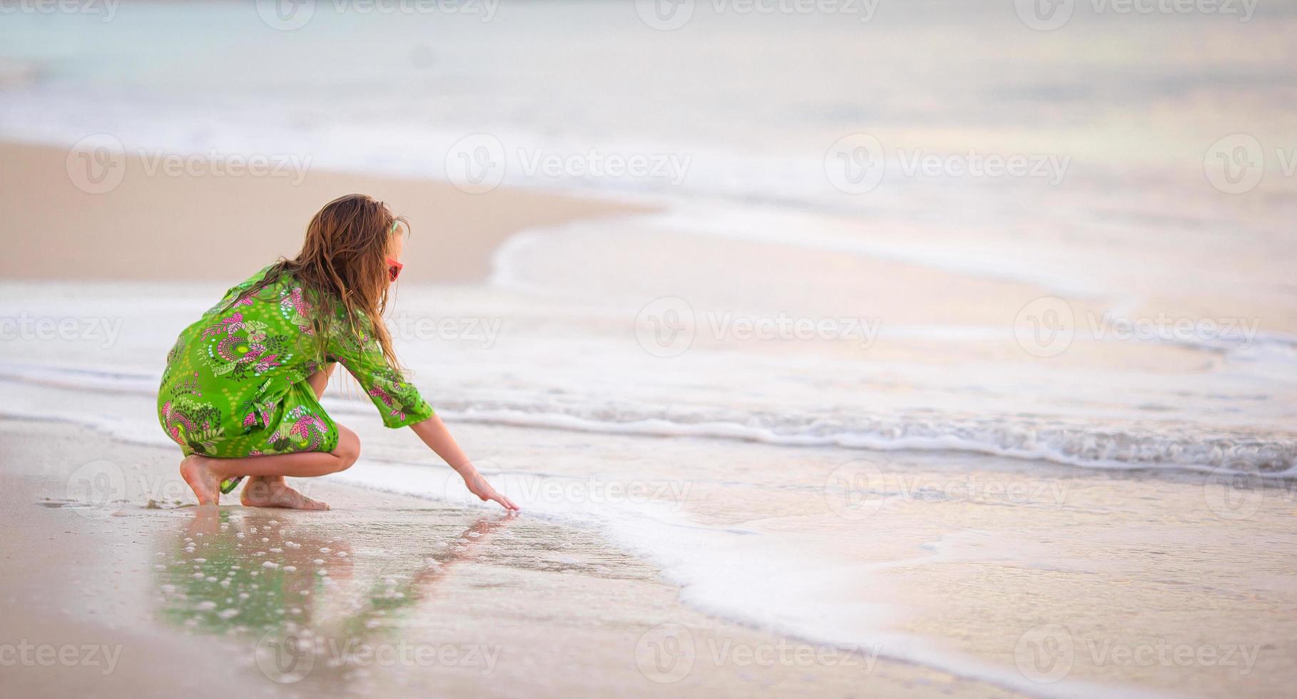 bedårande liten flicka ha kul på den tropiska stranden under semestern foto