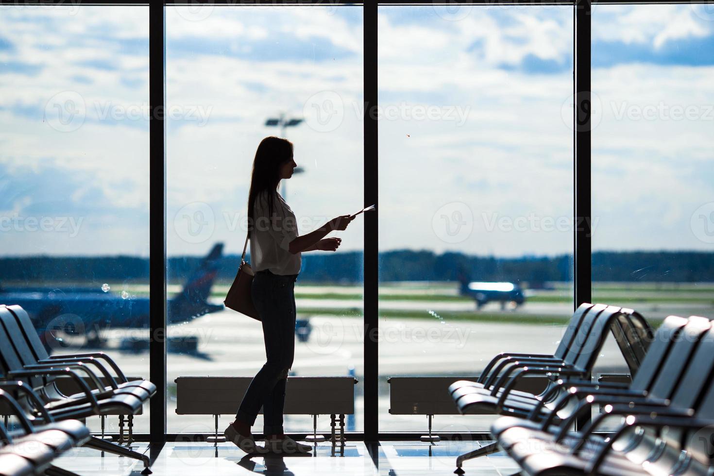 silhuett av flygbolag passagerare i ett flygplats vardagsrum väntar för flyg flygplan foto