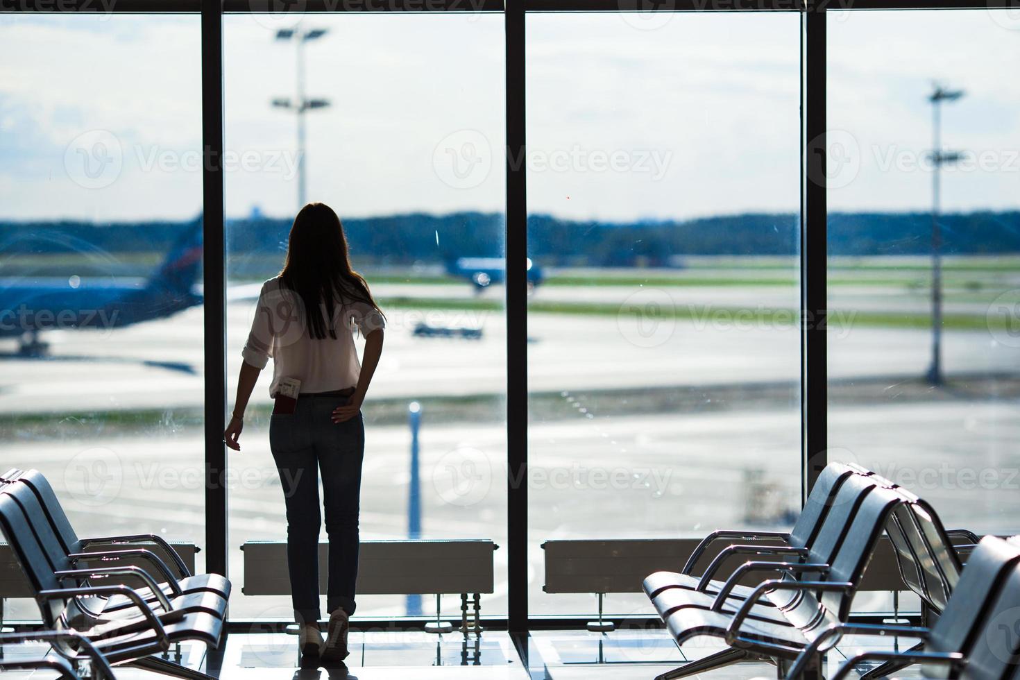 silhuett av flygbolag passagerare i ett flygplats vardagsrum väntar för flyg flygplan foto