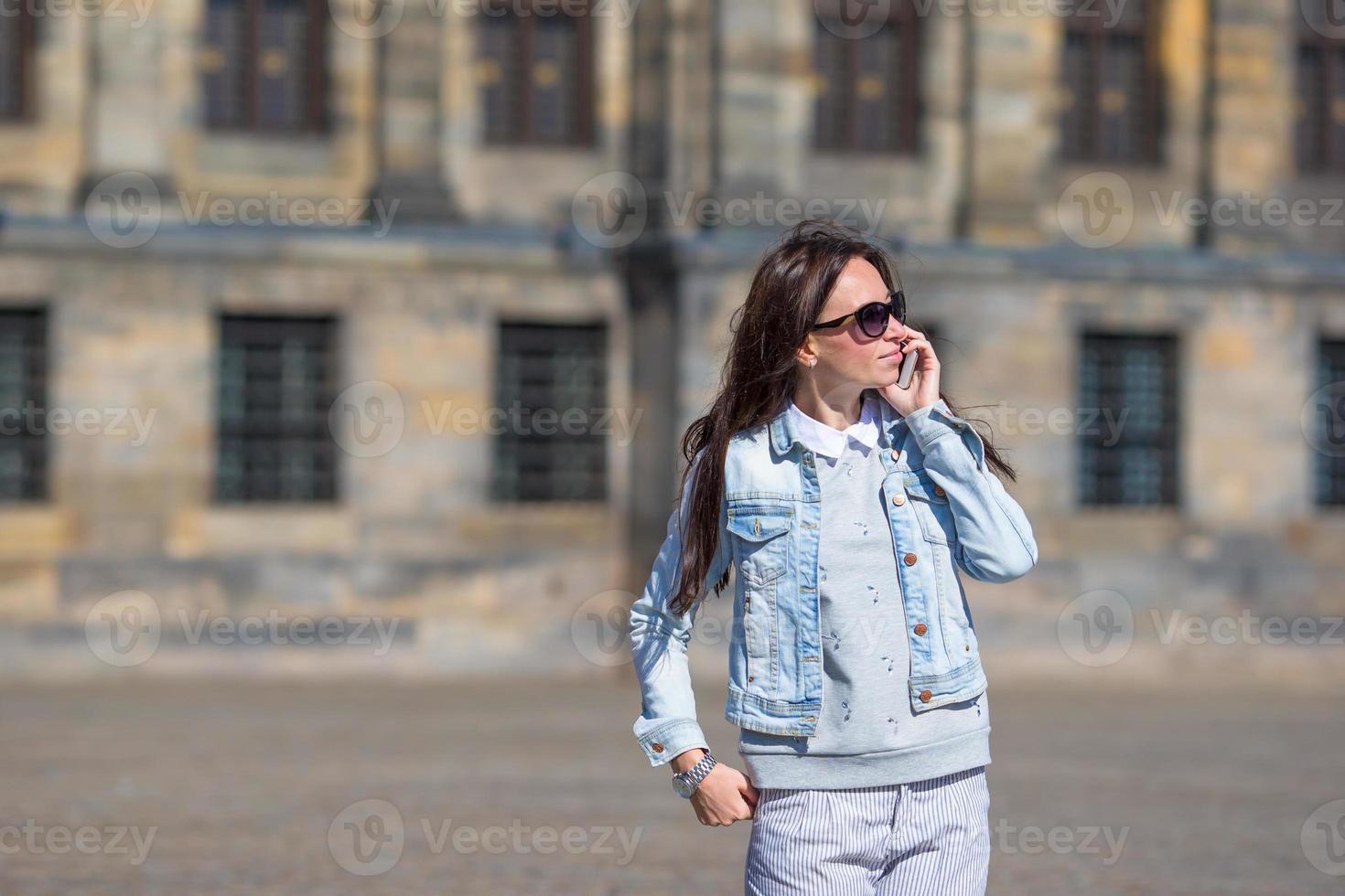 ung caucasian kvinna talande förbi cell telefon på gammal gator i europeisk stad foto