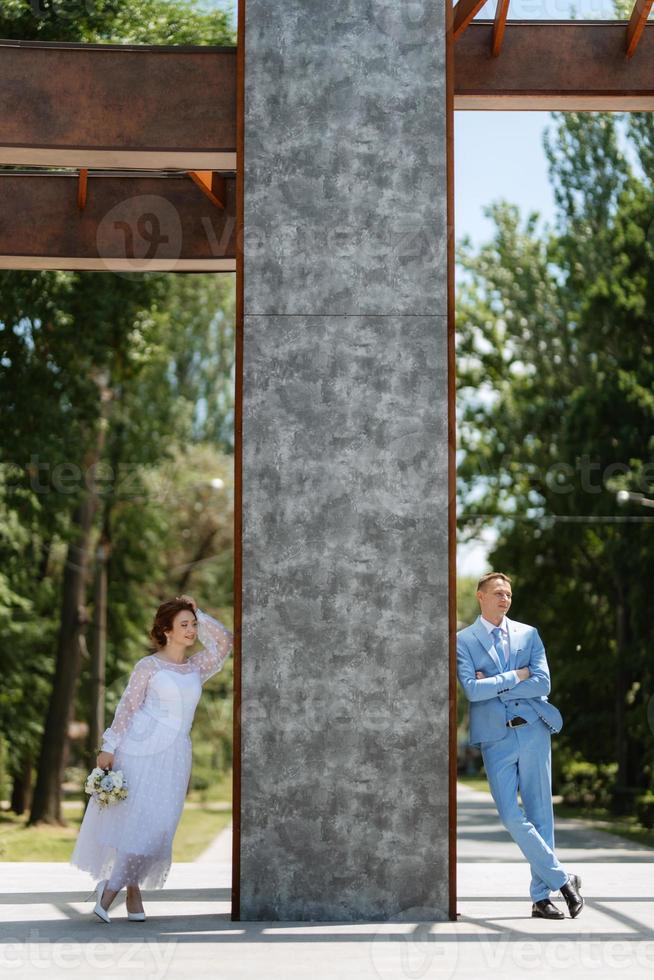 brud i en ljus bröllop klänning till de brudgum i en blå kostym foto