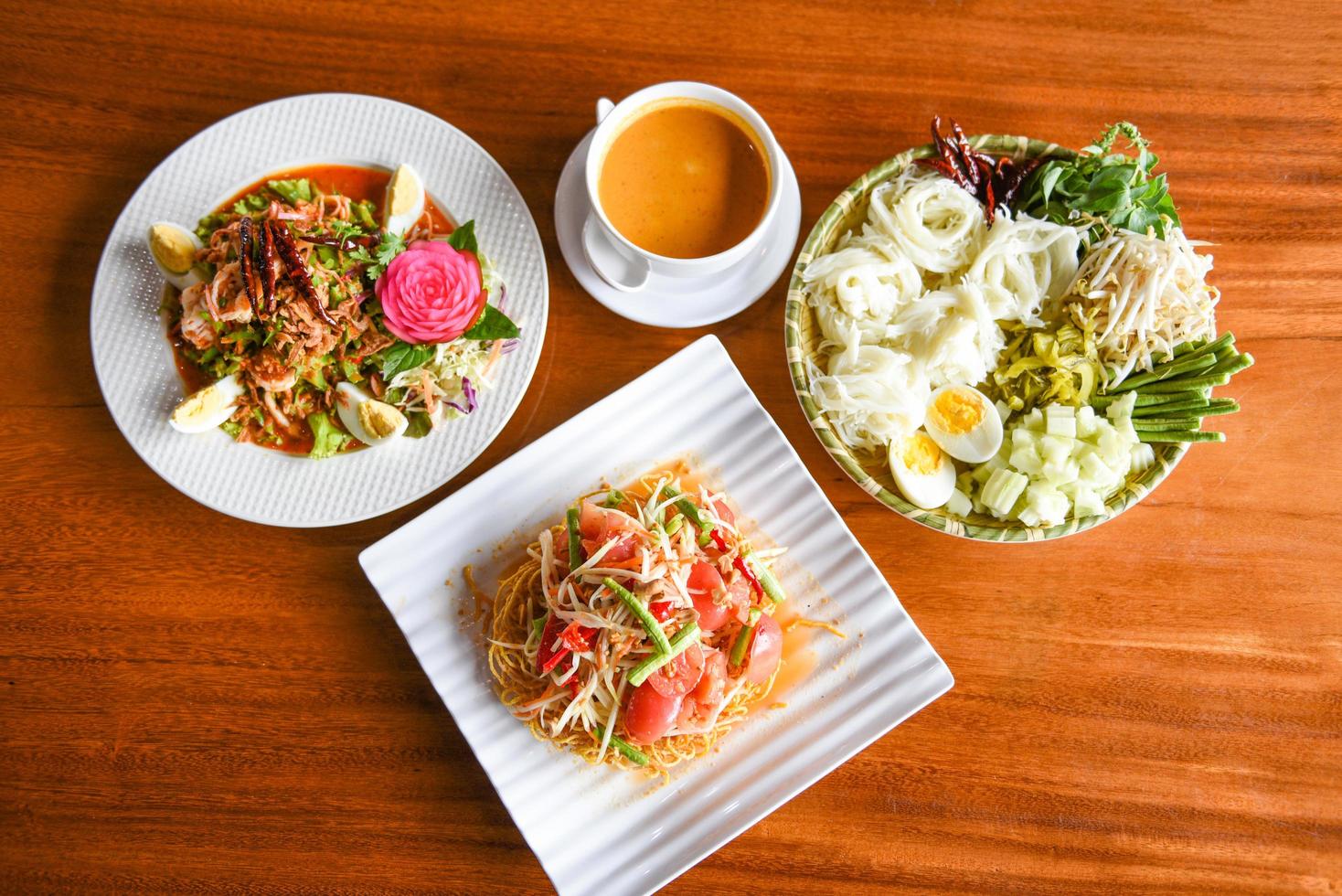 asiatisk thai mat topp se med thai ris spaghetti , curry papaya sallad , räka sallad mat eras på trä- tabell miljö tallrik foto