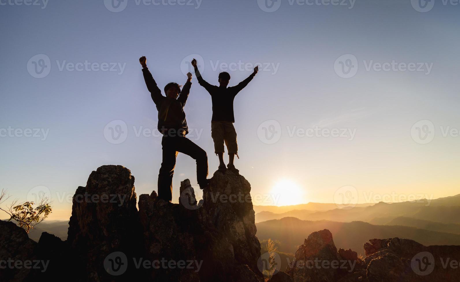 silhuett av lagarbete av två män vandrare portion varje Övrig på topp av berg klättrande team. lagarbete vänskap vandring hjälp varje Övrig förtroende bistånd silhuett i berg, soluppgång. foto