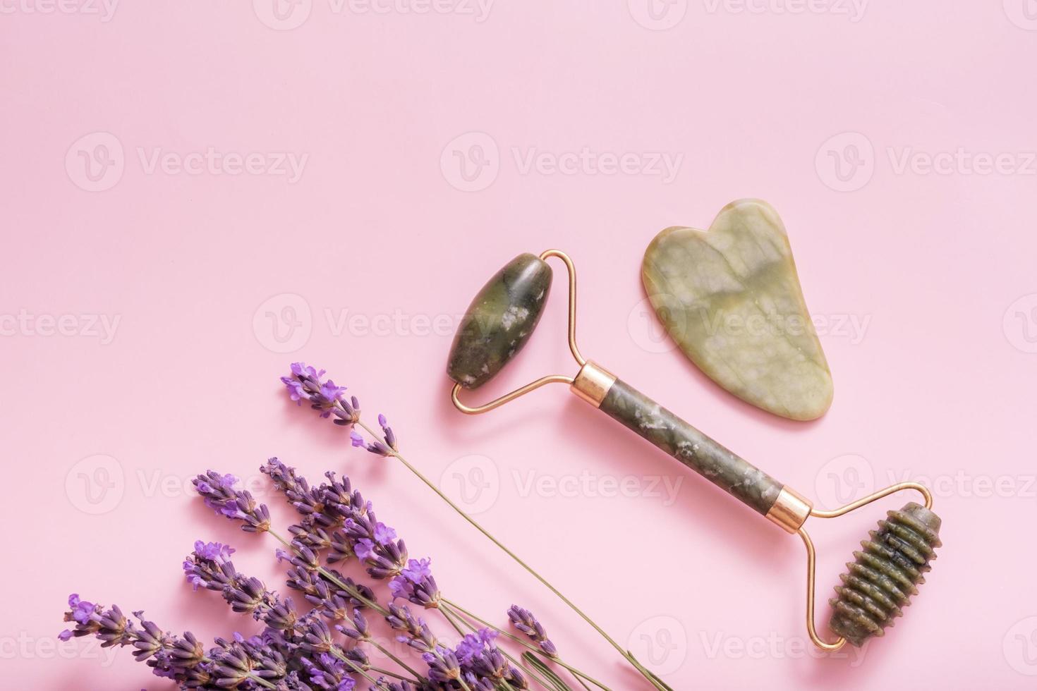 sten ansikte massageapparater med lavendel- blommor på färgad bakgrund topp se, platt lägga spa begrepp foto