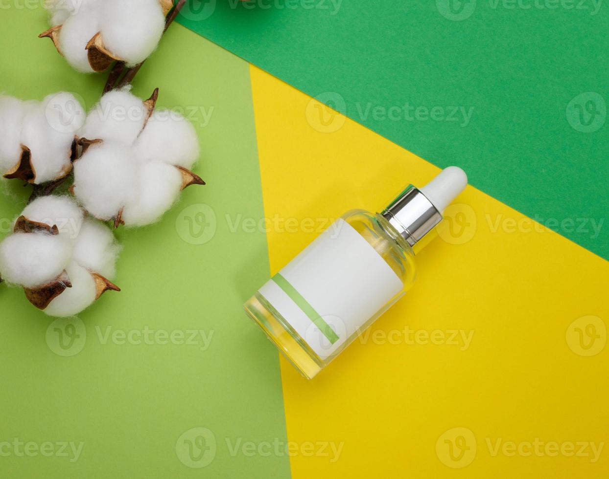 glas transparent vit flaska med en pipett. behållare för kosmetika, syror och oljor på en gul bakgrund foto
