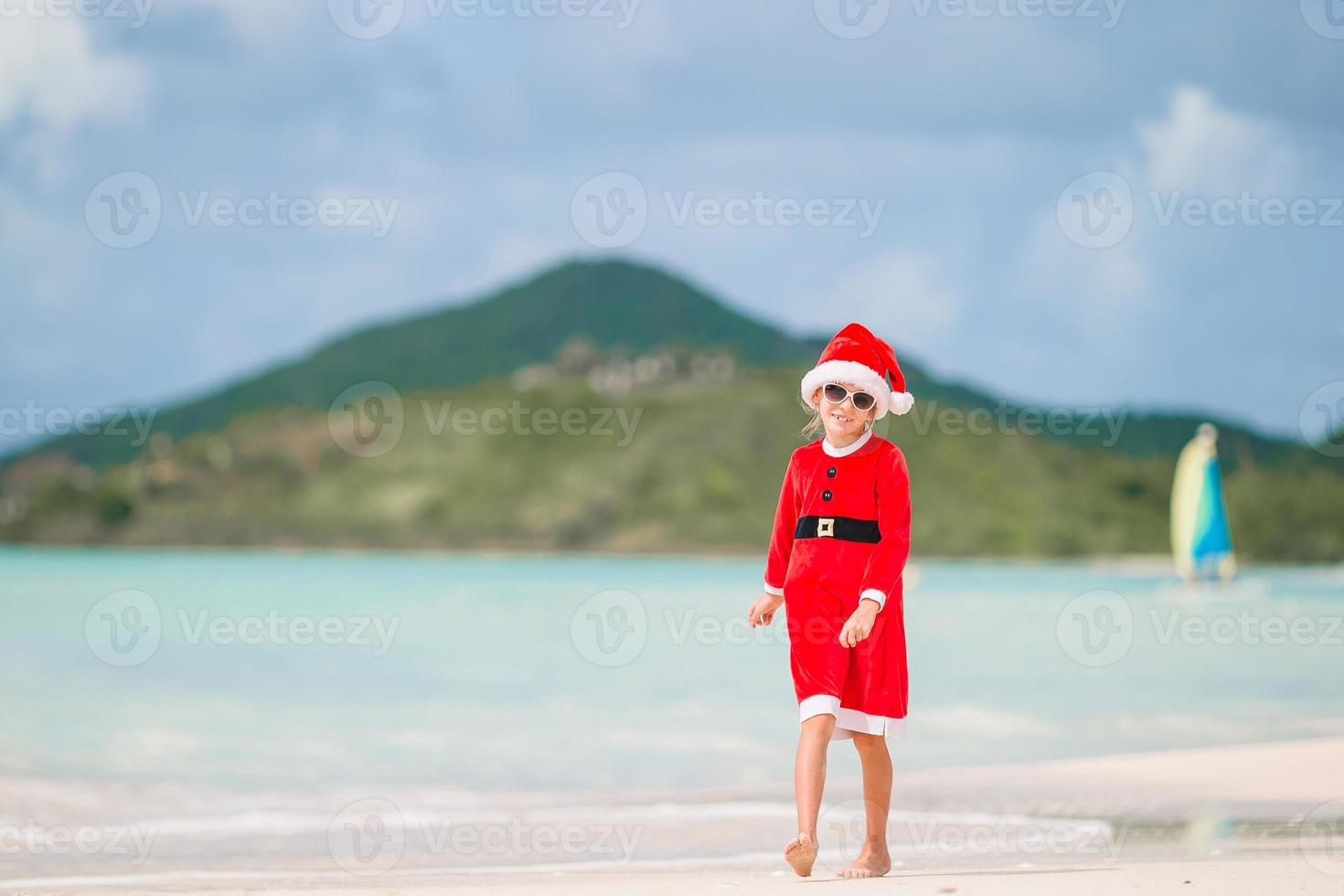 bedårande liten flicka i santa hatt på tropisk strand foto