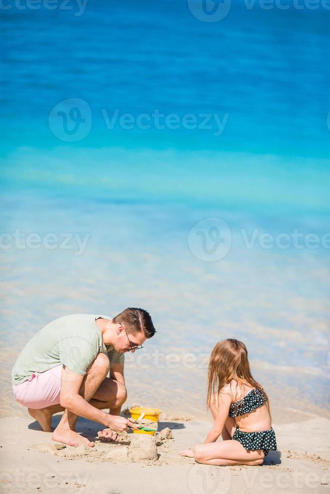 familj framställning sand slott på tropisk vit strand. far och flicka spelar med sand på tropisk strand foto