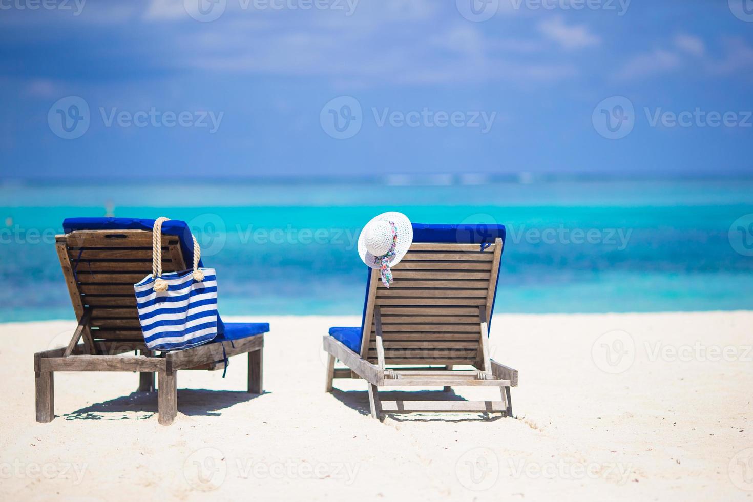 vit hatt och väska på vardagsrum stolar på tropisk sandig strand foto