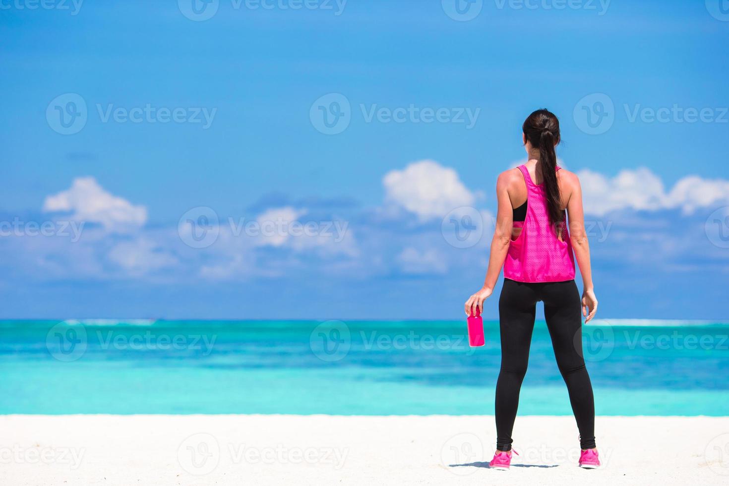 passa ung kvinna dryck vatten på vit strand foto