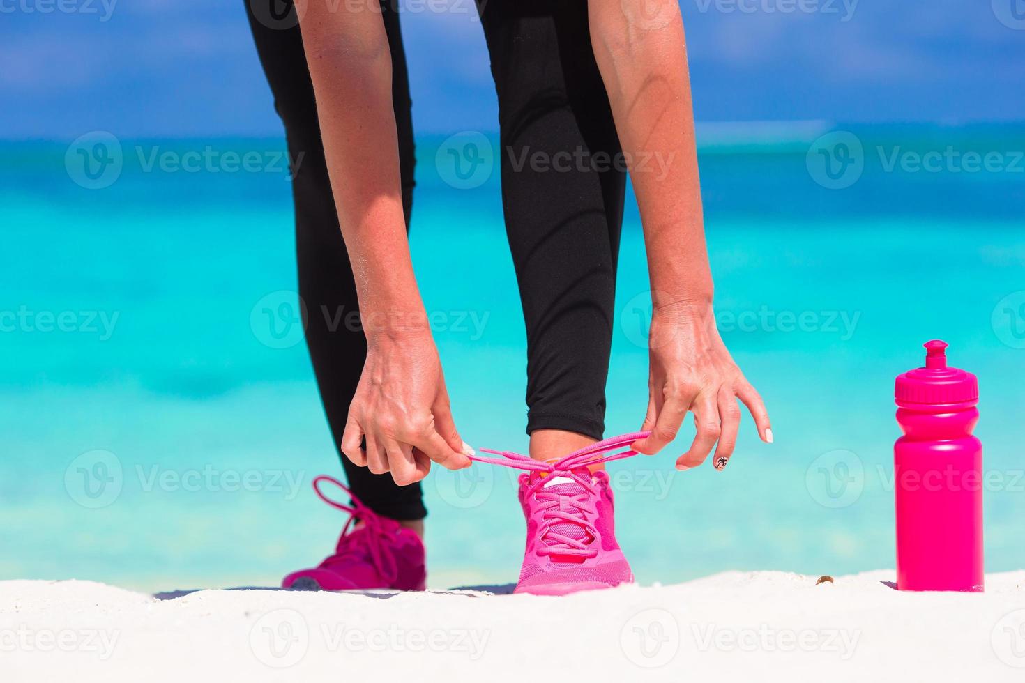 löpning kvinna kvitt löpning sko skosnören medan springa på vit strand foto