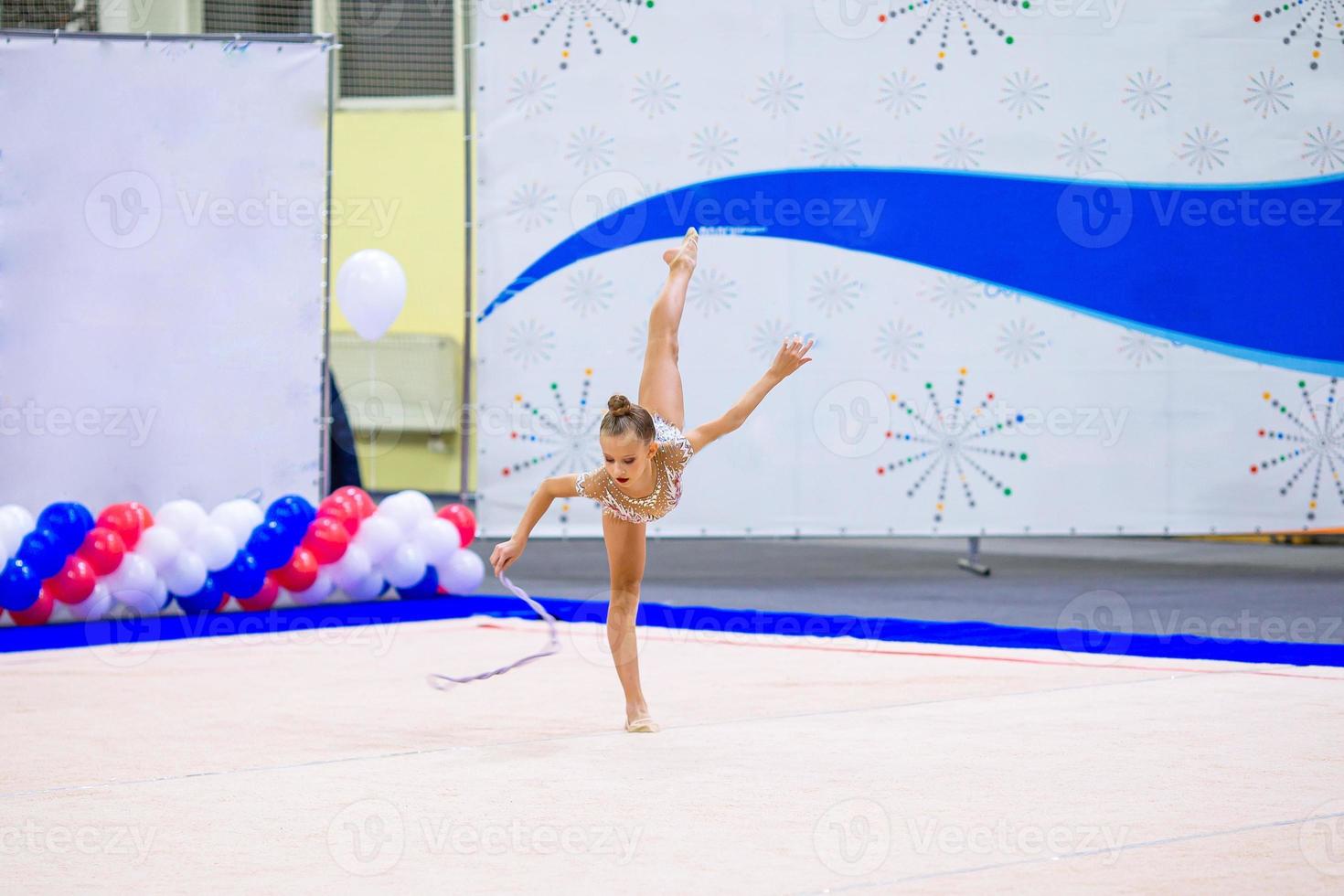 skön liten aktiva gymnast flicka med henne prestanda på de matta foto